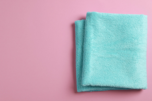 Soft folded light blue towel on violet background, top view. Space for text