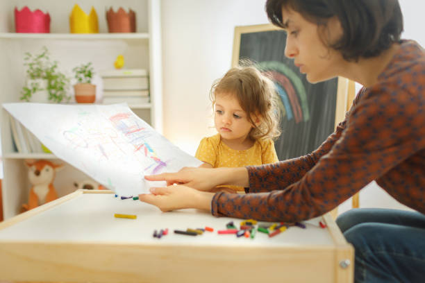 istock Mother and daughter sitting on the table and drawing. 1756766962
