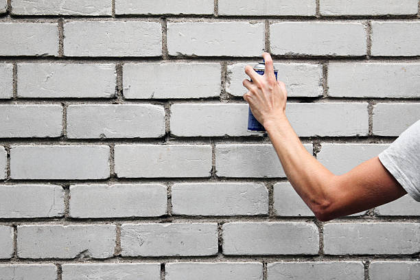 istock hand holding a graffiti spray can in front of wall 175676759