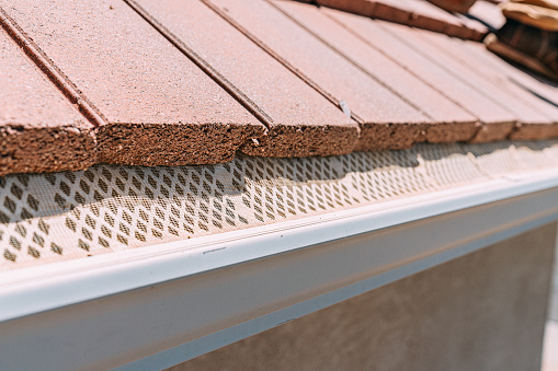 Mesh Guard Protecting an Aluminum Rain Gutter from Debris on a Clay Tile Roof on a Southwestern US Residence on a Sunny Day