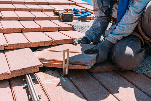 Professional Solar Installation Company Preparing a Clay Roof for Solar Panels on a Suburban Home with Clay Tiles in the Summer