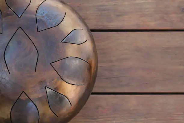 Steel tongue drum on wooden table, top view. Space for text