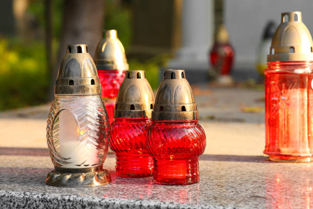 istock Different grave lanterns with burning candles on granite tombstone outdoors. Funeral ceremony 1756784611