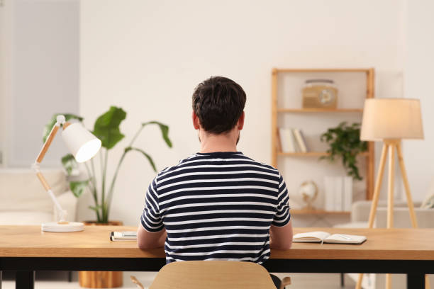istock Home workplace. Man working at wooden desk in room, back view 1756816315