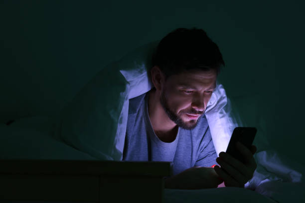 istock Man using smartphone under blanket in bed at night. Internet addiction 1756817402