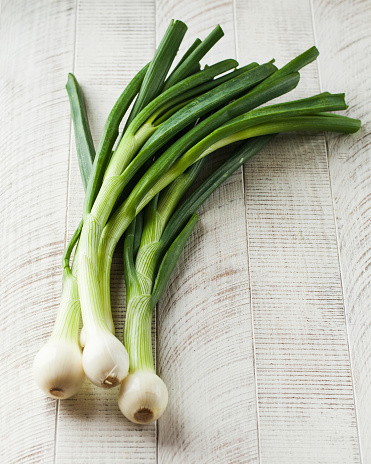 Young juicy spring onions on a white wooden background. The concept of healthy food, vegetables.
