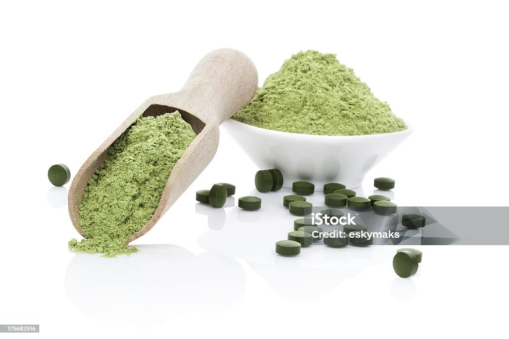 Wheatgrass powder and chlorella pills Wheatgrass powder, green chlorella and spirulina pills isolated on white background with reflection. Healthy living. Organic natural food supplement. Ground - Culinary Stock Photo