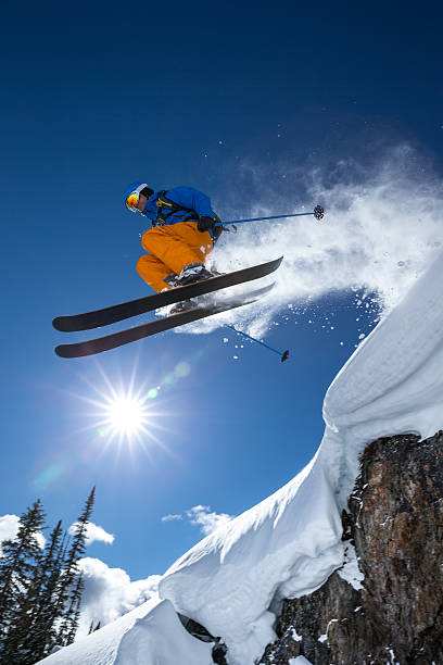 Person jumping off the mountain in extreme skiing stock photo