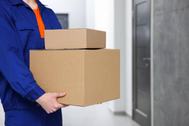 Courier with cardboard boxes in hallway, closeup stock photo