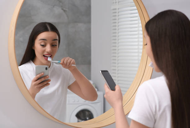 istock Beautiful young woman using smartphone while brushing teeth in bathroom. Internet addiction 1756838091