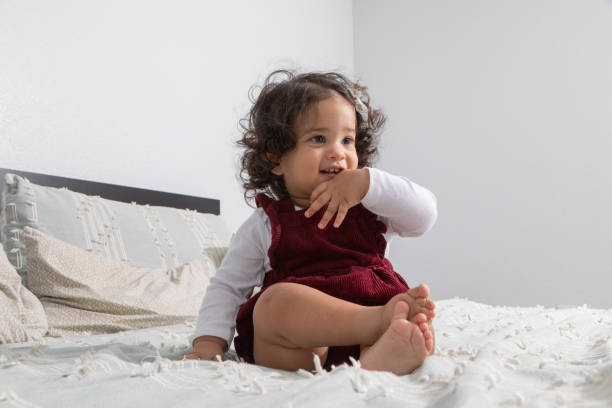 Baby girl with red dress in bed stock photo