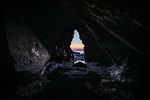 View out of a cave to the sea with sunset, on the Crozon peninsula, Brittany France