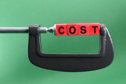 Letters of the word, COST on colored stack of red wooden cubes held by a steel clamp isolated on a green background. Abstract for financial concepts related to cost and budget control.