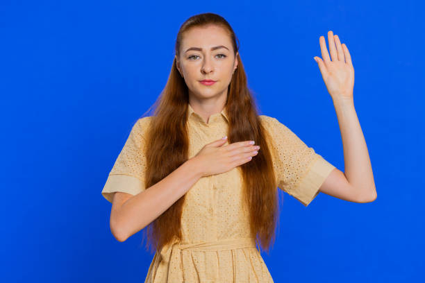 woman raising hand to take oath, promising to be honest and to tell truth, keeping hand on chest - proof of love imagens e fotografias de stock