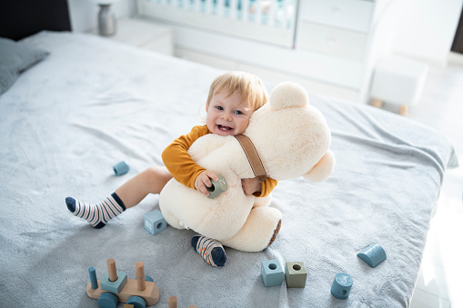 Joyful little cute boy hugging his favourite toy Teddy the bear.