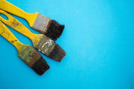 A background showing a well used palette and different styles of paint brushes.