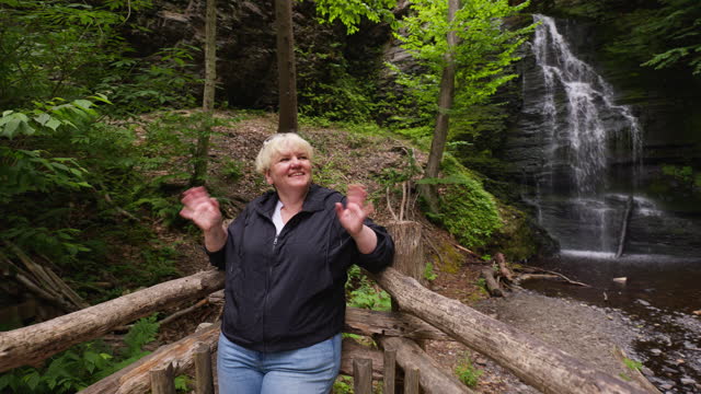 Domestic tourism, blonde woman trip to the main attractions at Bushkill Falls, Pocono Mountains in Pennsylvania. Footage with push to close-up camera motion