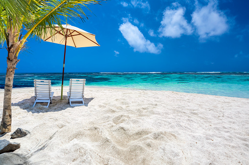 Beach shoot themes: Caribbean island white sand turquoise beach with umbrella, chairs and coconut trees. Morrocoy National Park, Venezuela