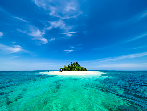Beautiful nonsettled tropical island with perfect sunset sky and azure water with corals