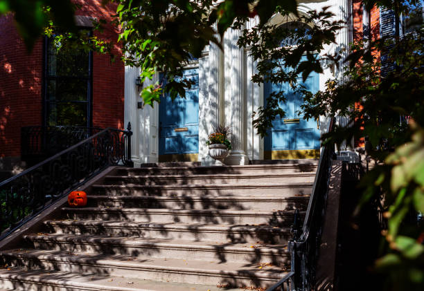 Building's entrance with two blue doors and a stoop with a broken orange pumpkin. Celebrating the Autumn season. Selective focus.