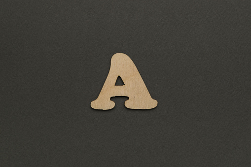 Wooden letter A on a dark gray background. English alphabet.