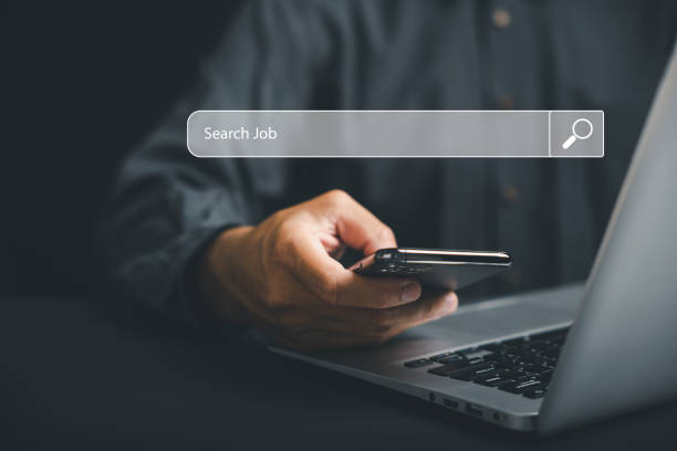 스마트폰을 들고 있는 남자가 화면에서 일자리를 찾는다 스톡 사진