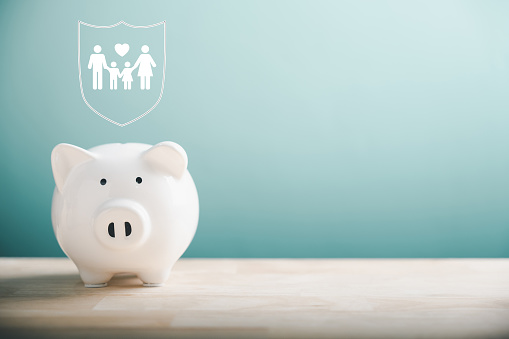 Piggy bank, family icon nearby, on desk. Family life insurance concept. Symbolizing financial security, safe education, health budget, and wealth accumulation. Representing family economic well-being.