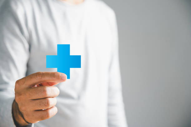Isolated, a male hand securely holds a plus icon, embodying addition of positives, benefits, personal growth, health insurance, and growth. Emphasizes innovation in health care and technology.