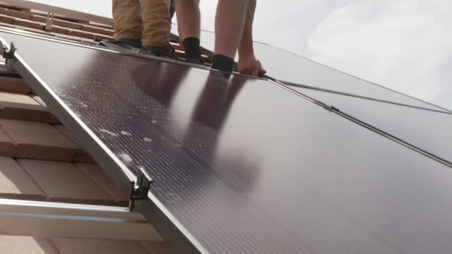 Young Man Positioning a Solar Panel on a Suburban Western USA Home