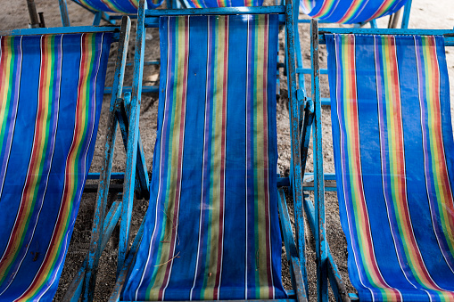 A row of blue canvas beds under beach umbrellas await visitors at Thailand.
