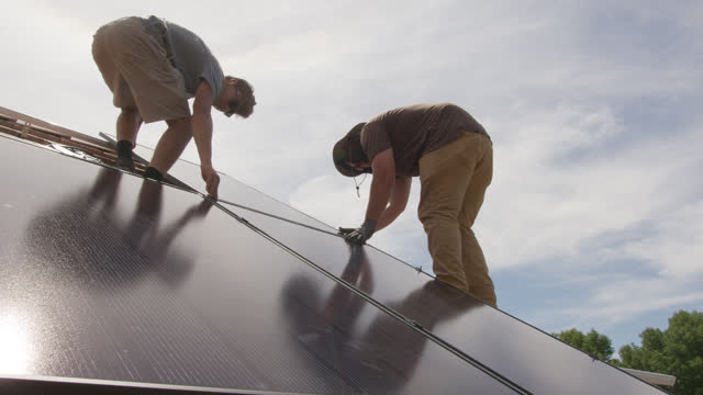 Two Young Men Working Together Installing Solar Panels on a Suburban Western USA Home