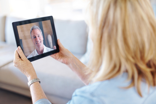 Senior woman receiving a video call from her husband on a tablet
