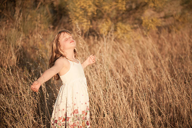 Blonde girl breathing with open arms in the countryside at sunset