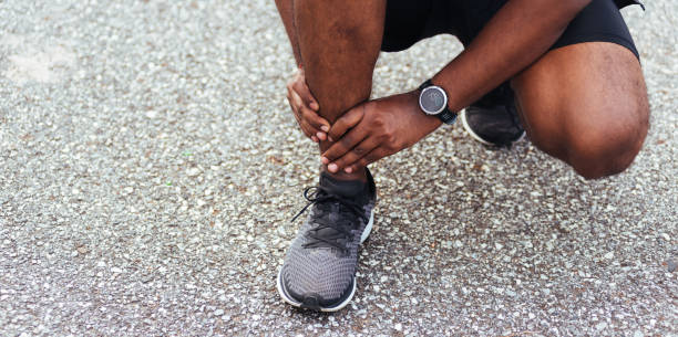 homem corredor esporte usar mãos articular dor perna por causa de tornozelo torcido quebrado durante a corrida - pain human muscle effort physical injury - fotografias e filmes do acervo