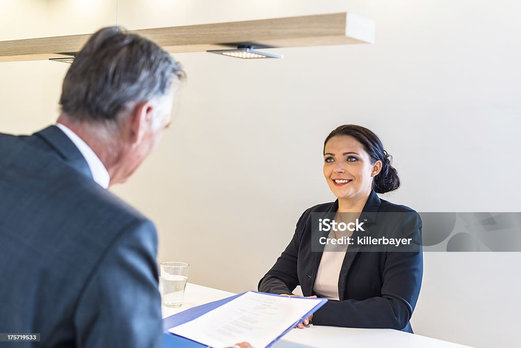 Job interview Recruiter (middle aged business man) checking the candidate, an attractive younger woman,  during job interview Adult Stock Photo