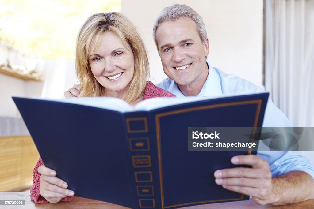 Remembering the past fondly Happy senior couple smiling while looking through a photo album together 50-59 Years Stock Photo