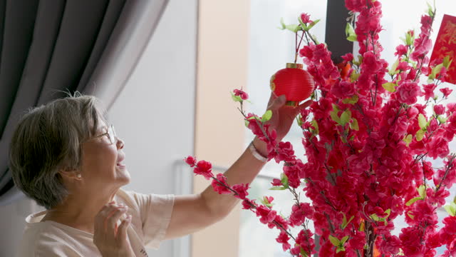 Senior woman decorating house for Chinese New Year celebration