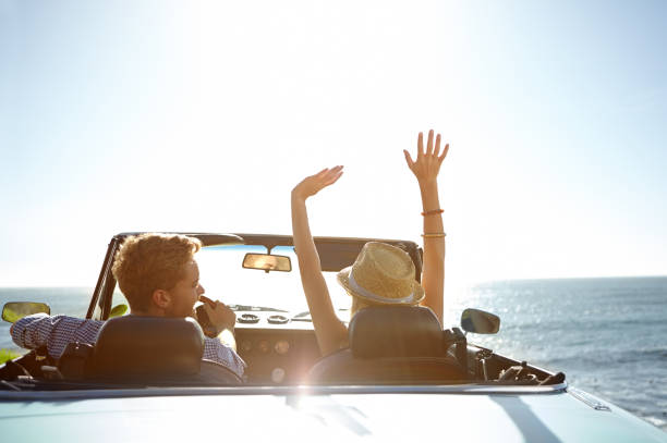 The perfect start to a holiday! A happy young couple parked by the ocean in a convertible on a sunny day convertible stock pictures, royalty-free photos & images