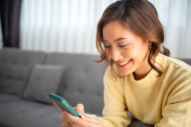 istock woman sitting on a sofa using a mobile phone, Happy relaxed smiling lady laughing holding smartphone, looking at cellphone enjoying doing online e-commerce shopping in mobile apps or watching videos. 1757203374