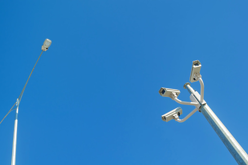 Security CCTV cameras and streetlight against blue sky