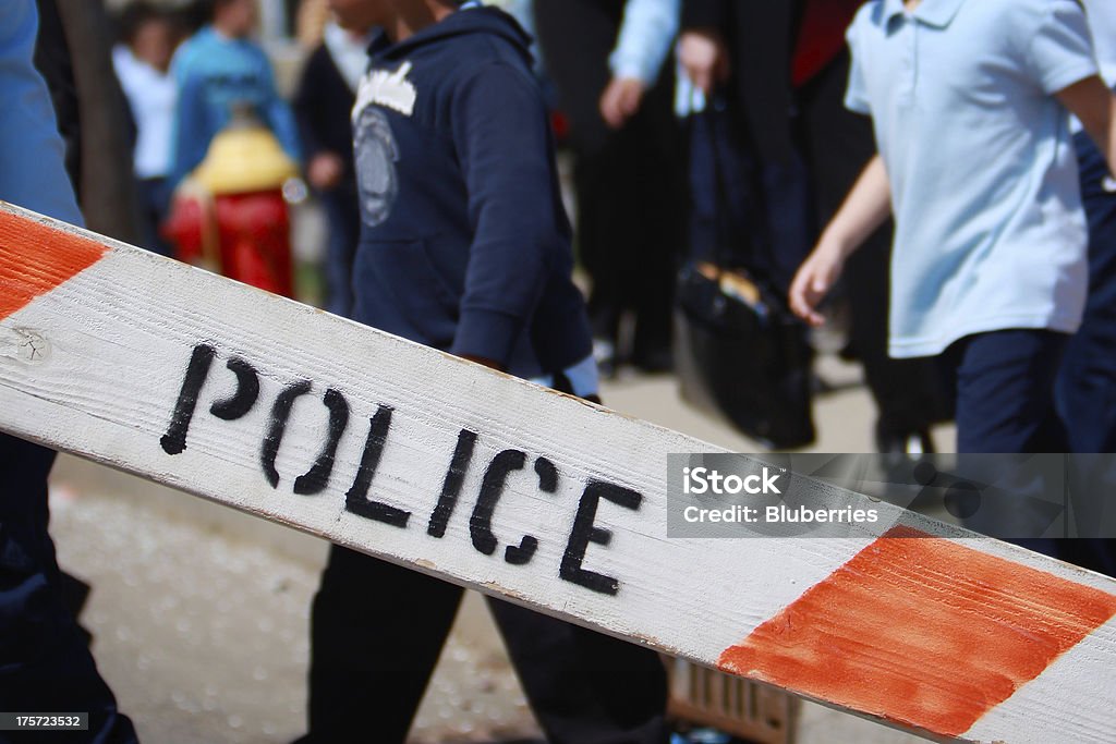 Police Evacuation Colice barricade with children in the background. Focus on the Police barricade. School Building Stock Photo