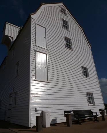 Image of historically significant Woodbridge tidal mill in Suffolk, England. The photo is shot from a prone position with a wide lens angle distorting the image and giving the impression that the building is falling backwards. 