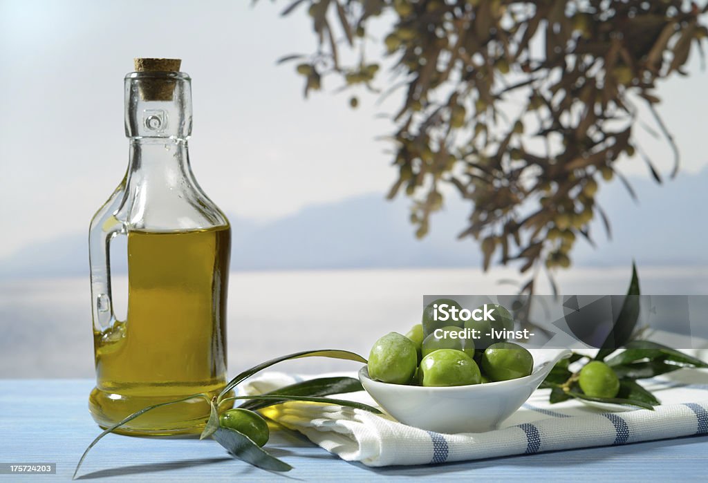 Olives, olive branch and olive oil Olives and olive oil against Mediterranean landscape Blue Stock Photo