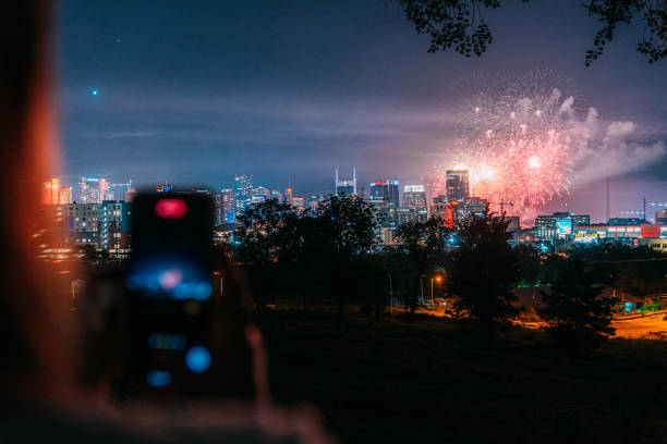 Person Using a Mobile Device to Record Independence Day Fireworks over Downtown Nashville, Tennessee Skyline