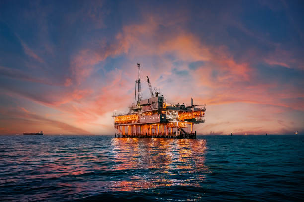 カリフォルニア州オレンジカウンティ沖のオフショア石油掘削リグの背後にある鮮やかな夕焼け空