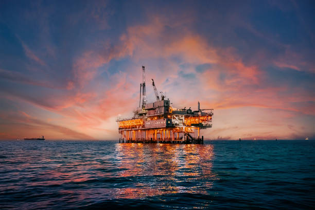 céu vibrante do pôr do sol atrás de uma plataforma de perfuração de petróleo offshore na costa do condado de orange, califórnia - oil rig sea oil well oil drill - fotografias e filmes do acervo