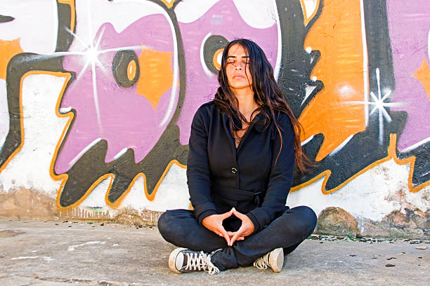 istock Young woman meditating at a graffiti brick wall 175727858