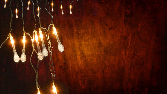 Dark brown colored wooden textured 3D or three dimensional horizontal blank Xmas or Diwali celebrations festive background, poster or wallpaper. Can be used as Christmas party wallpaper, backdrop, celebration, festive background, gift wrapping sheet. There are several lights hanging leaving plenty of copy space.