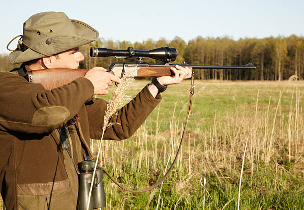 A game ranger in the outdoors aiming with his sniper rifle
