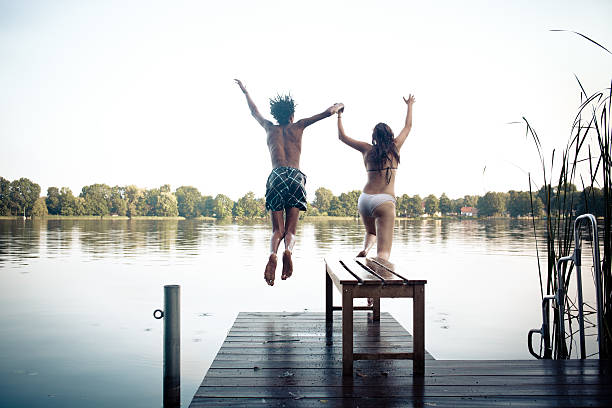 istock carefree summer day: teenagers jumping into a lake 175730747